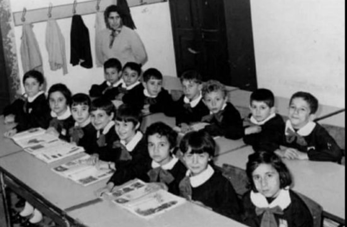 La scuola di una volta: grembiulini neri, quaderni a quadretti e una maestra -