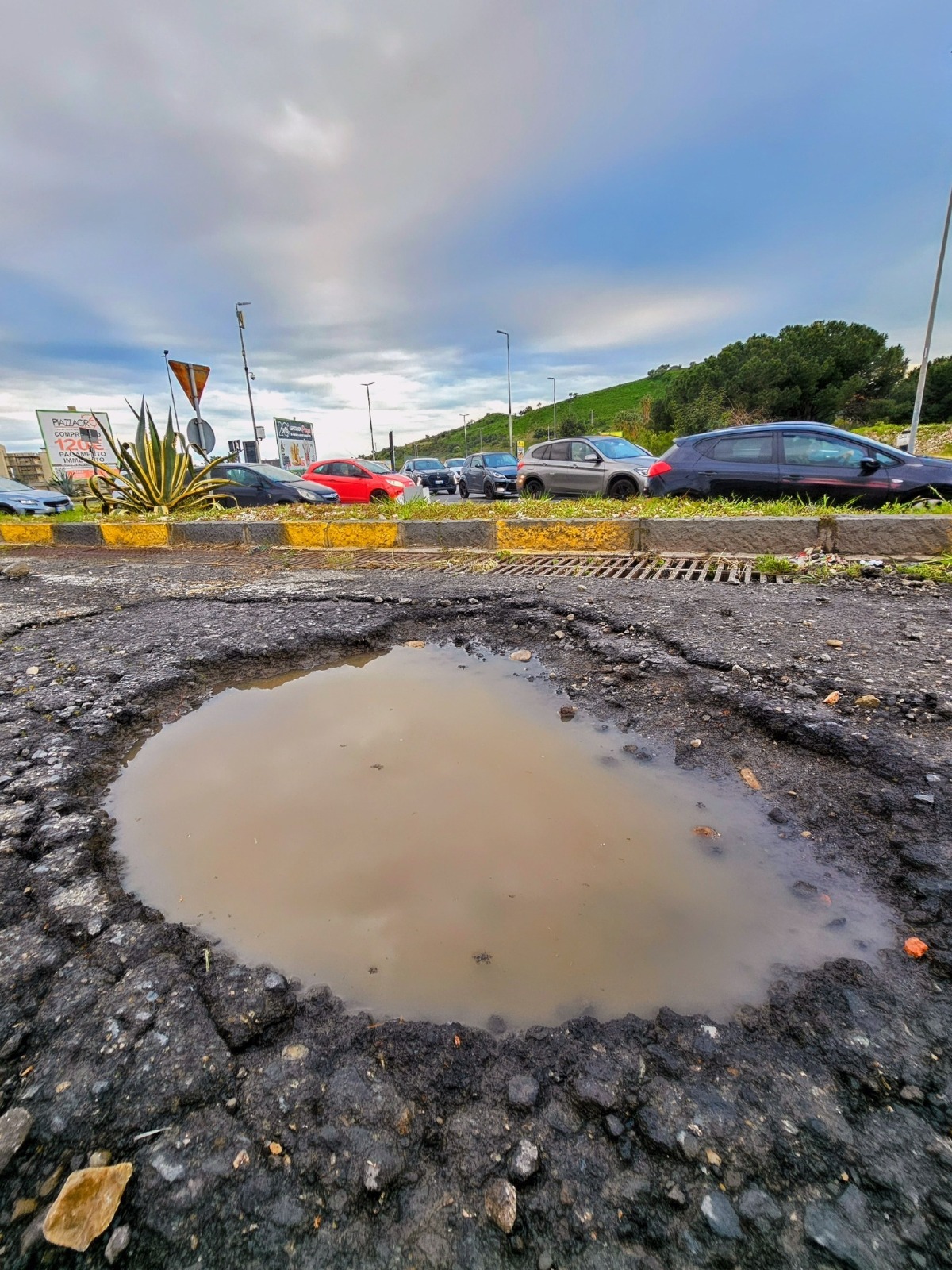Catania, profonda buca d'acqua alla rotonda dell'ospedale di Nesima segnalata sui social - Credit Foto Inciviltà a Catania